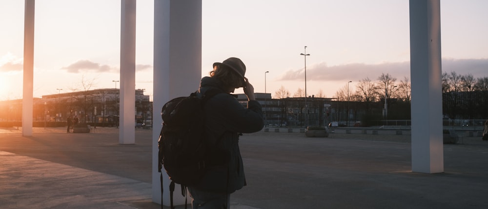 man in black jacket standing near white post during daytime