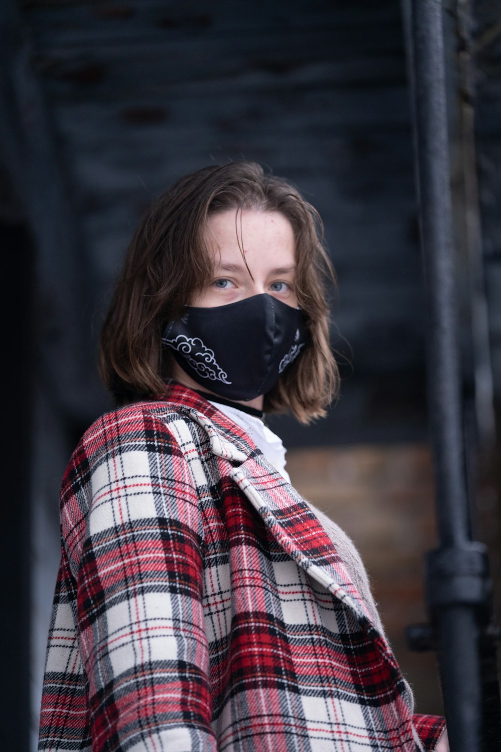 woman in red white and black plaid dress shirt wearing black mask