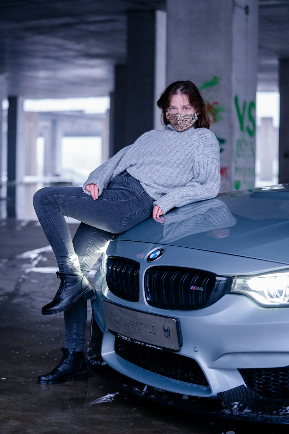 man in gray sweater and blue denim jeans sitting on black bmw car