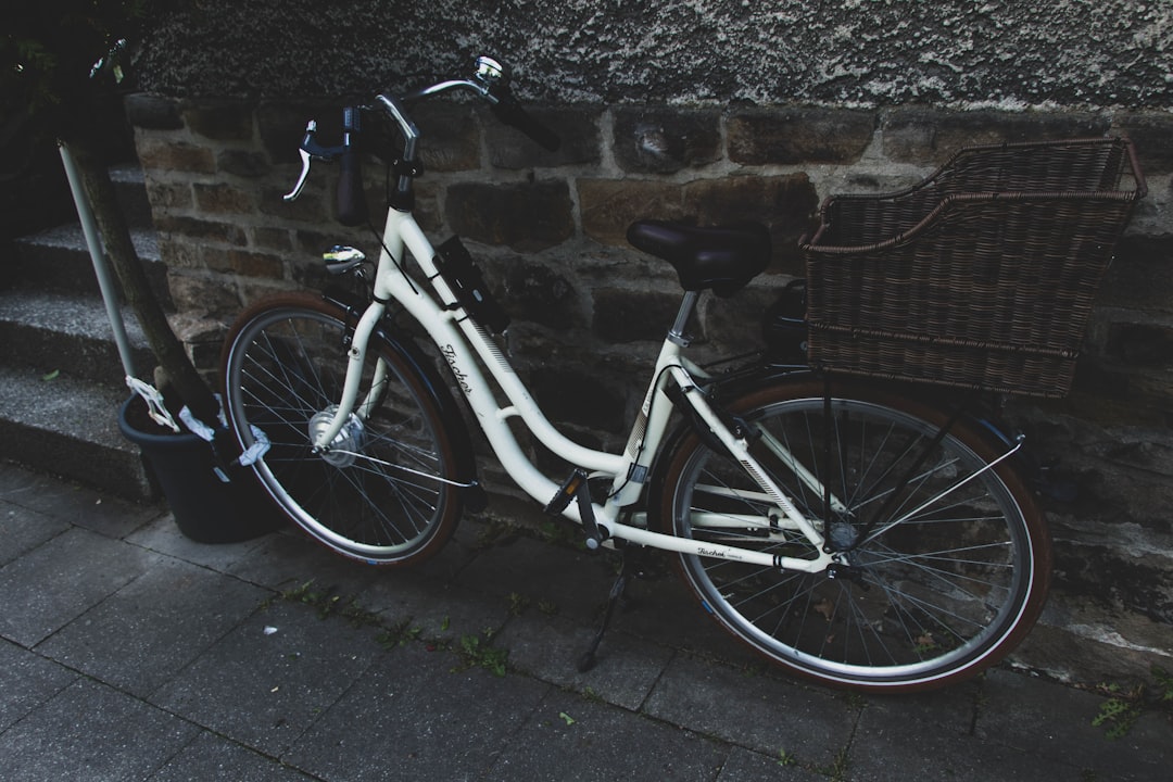white city bike parked beside brown brick wall