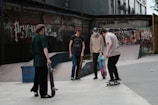 Group of friends showcasing different printed t-shirts in a city skate park.