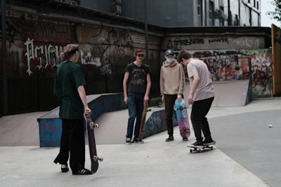 Group of friends showcasing different printed t-shirts in a city skate park.