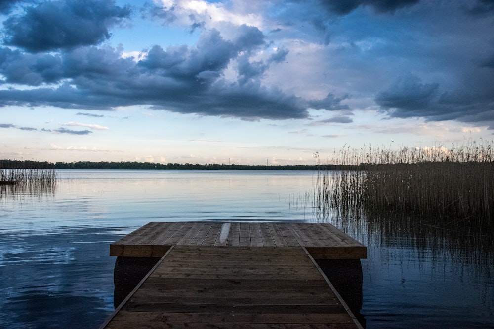 brown wooden dock on body of water under cloudy sky during daytime