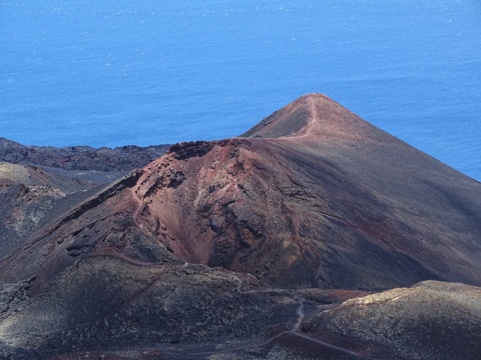 Mountain peak dominates a rocky landscape with a winding trail leading up to it