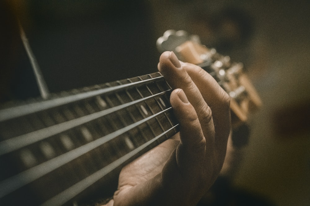 person playing guitar in grayscale photography