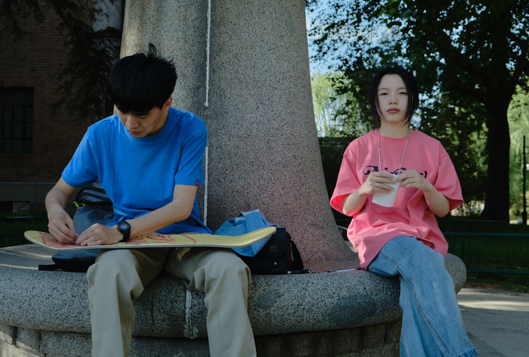 man in blue crew neck t-shirt and brown pants sitting on gray concrete bench,