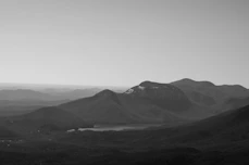 grayscale photo of mountains under cloudy sky