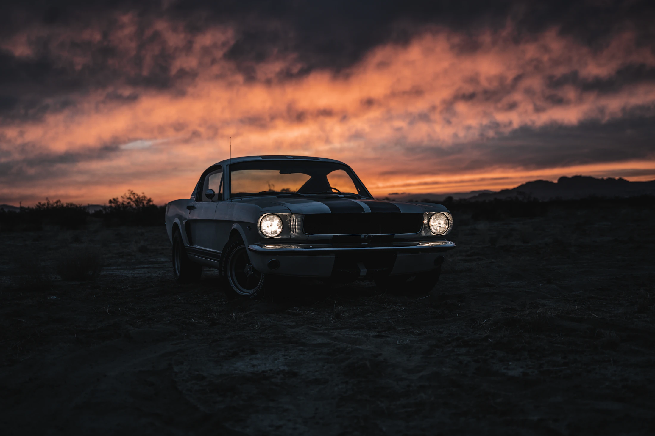 Vintage Ford Mustang on an open desert road at sunset