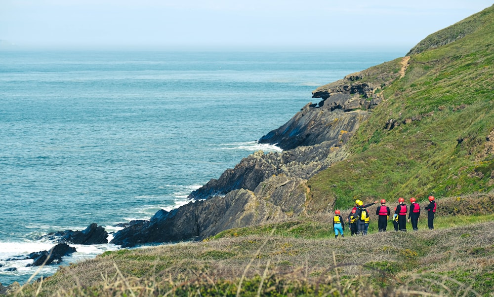 people hiking on rocky mountain near sea during daytime