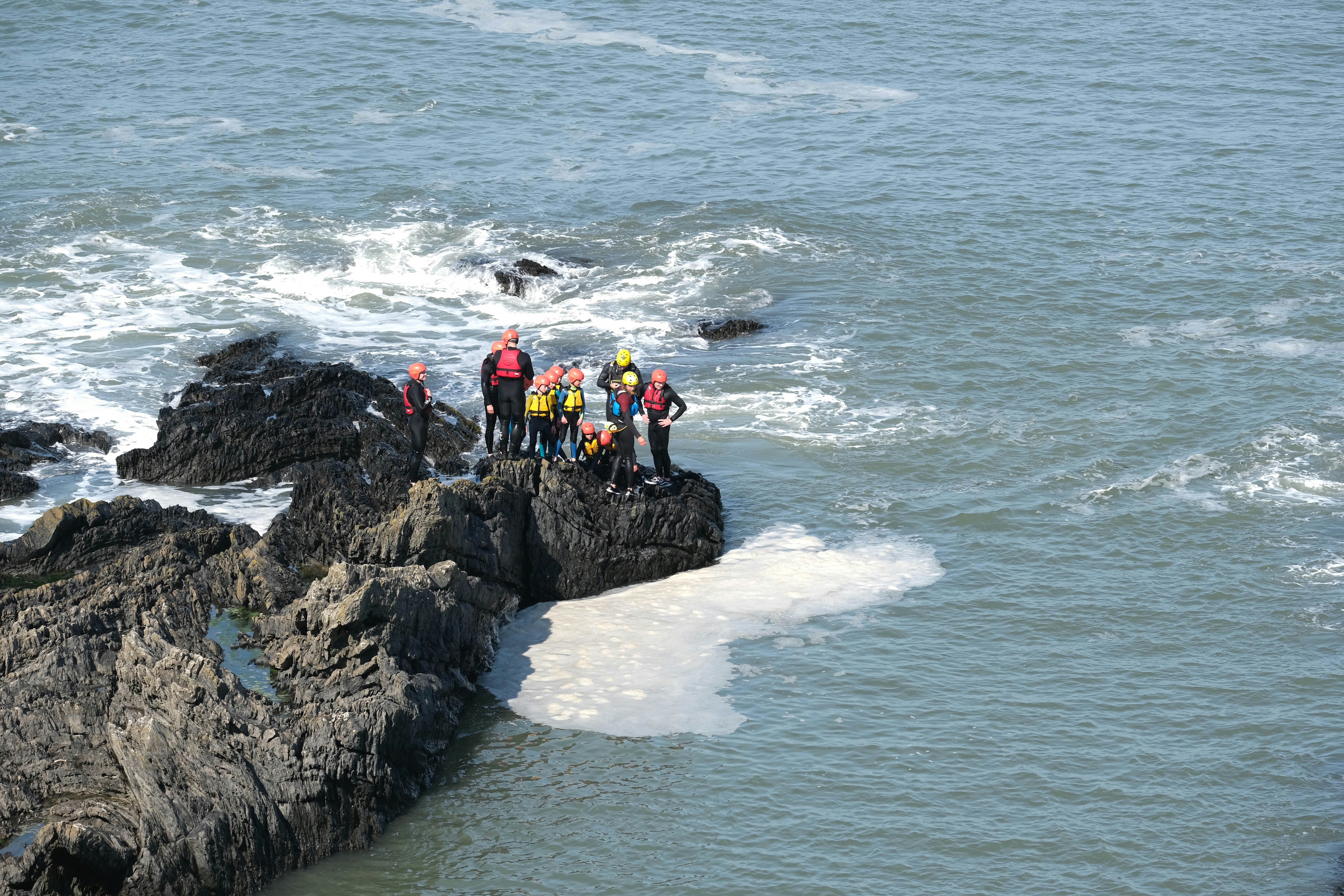 2 person sitting on rock formation near sea during daytime