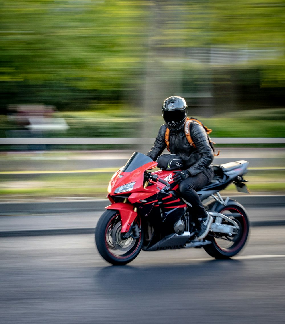 赤いスポーツバイクに乗る黒いヘルメットの男