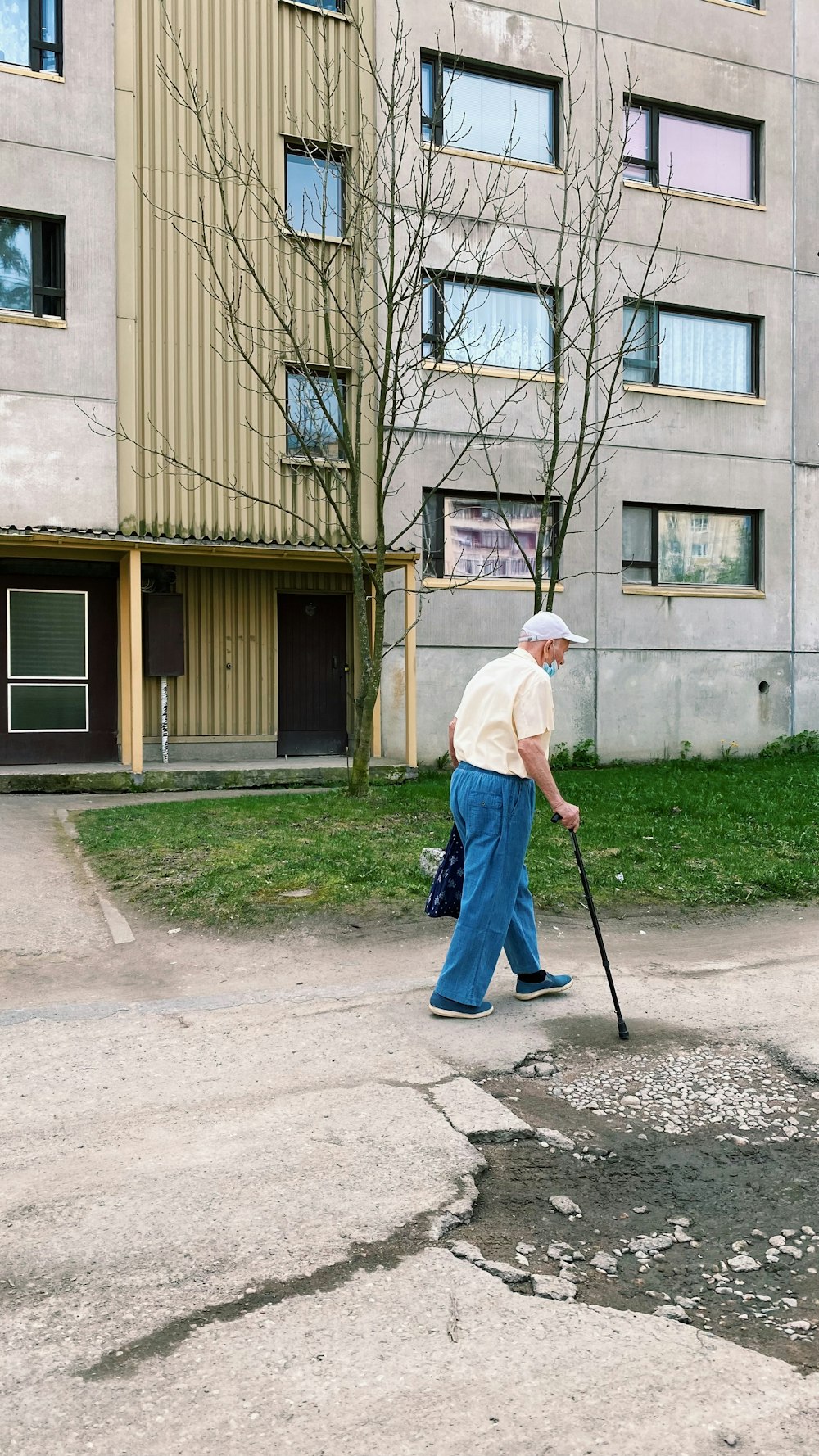 man in white dress shirt and blue denim jeans holding walking stick