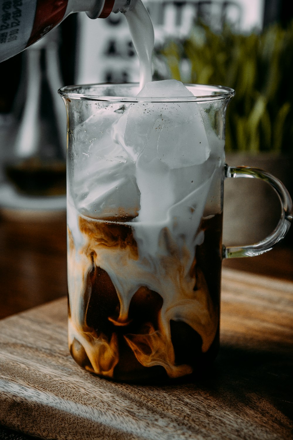 caneca de vidro transparente com cubos de gelo e líquido marrom