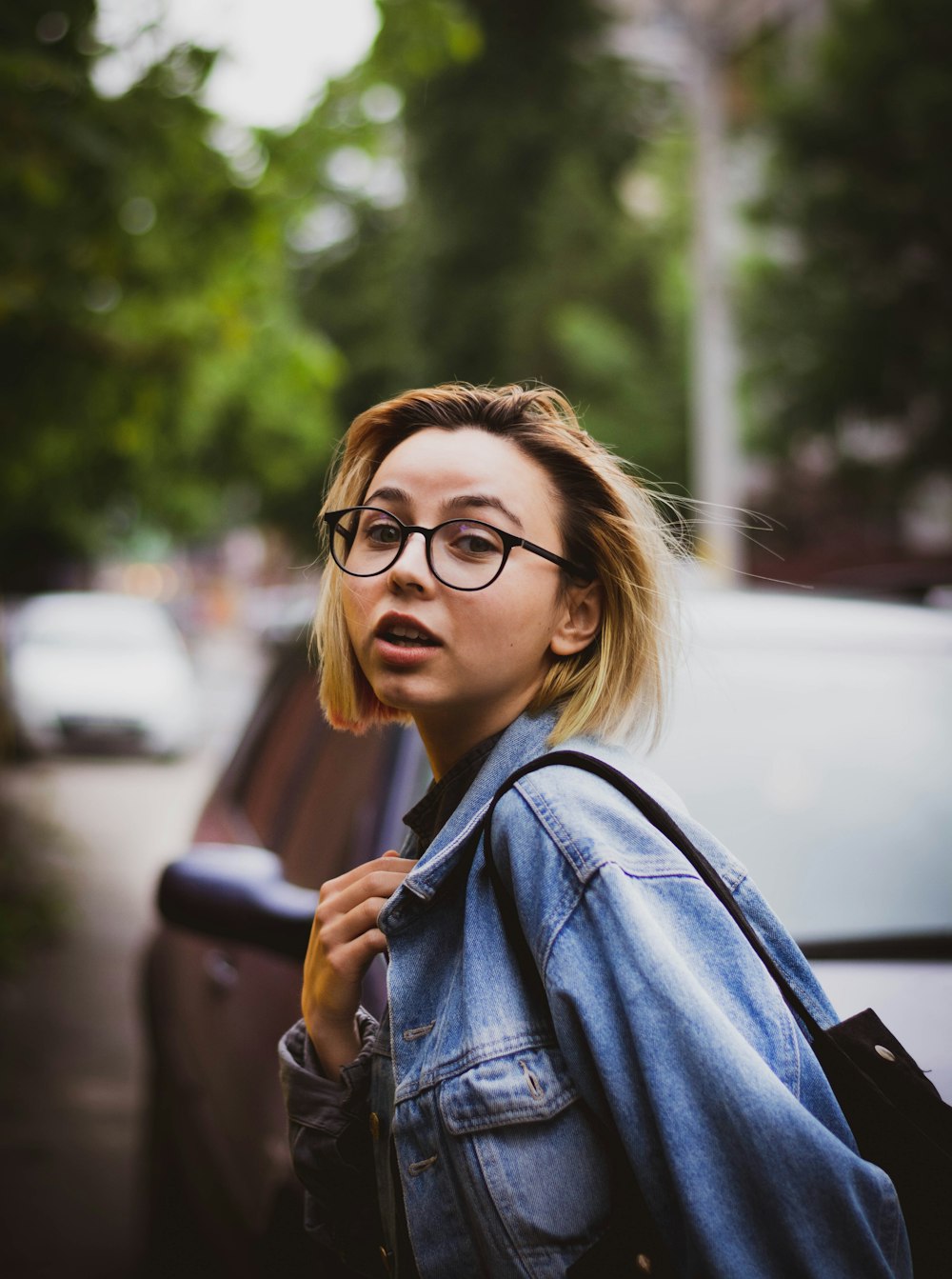 woman in blue denim jacket wearing black framed eyeglasses