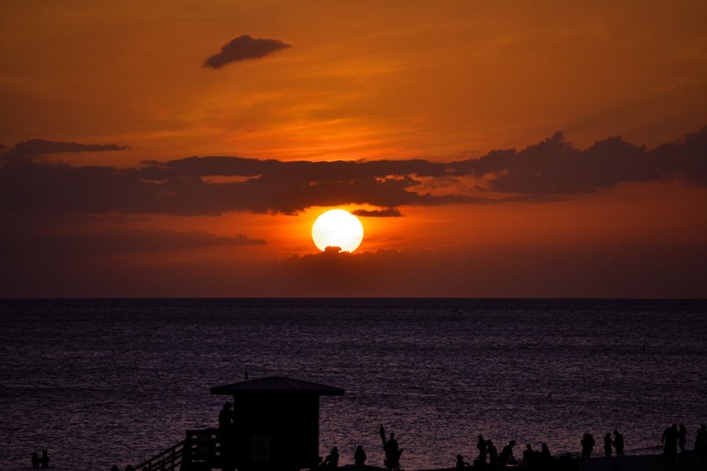 silhouette of people standing on beach during sunset