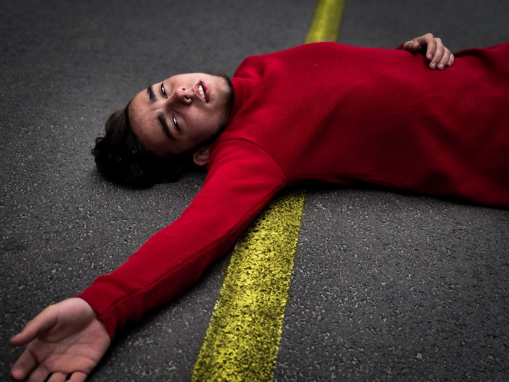 woman in red long sleeved shirt lying on the road