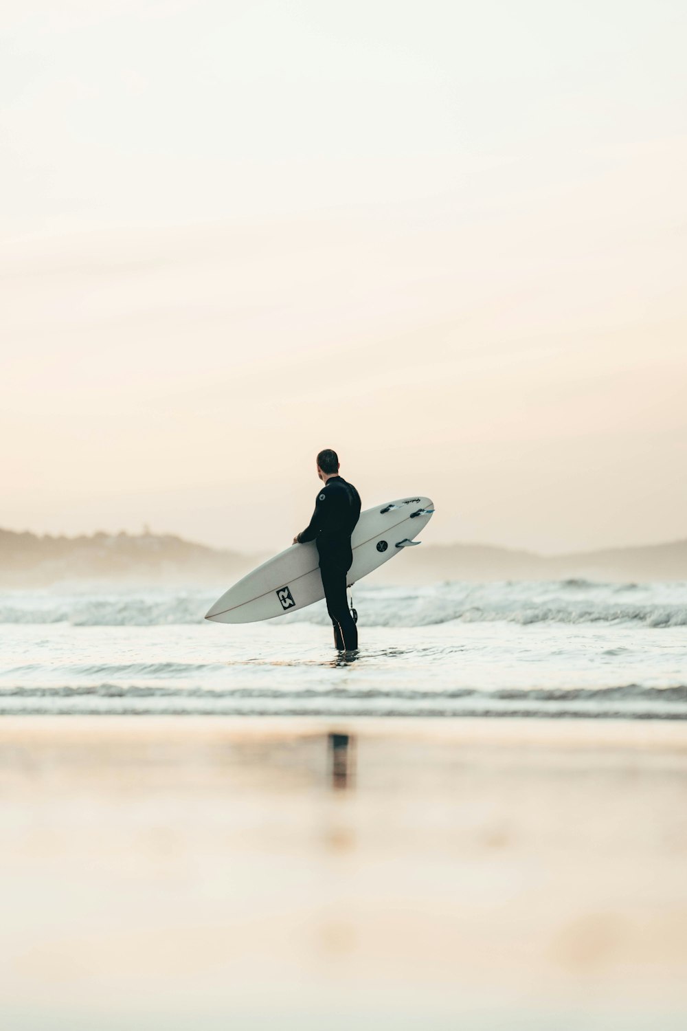 man in black wet suit holding white surfboard on beach during daytime