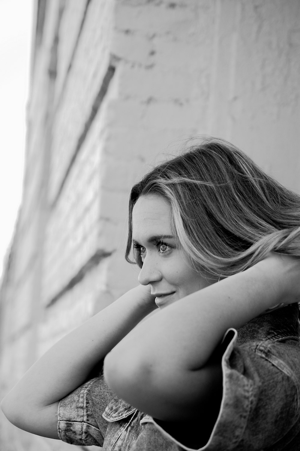 grayscale photo of woman leaning on wall