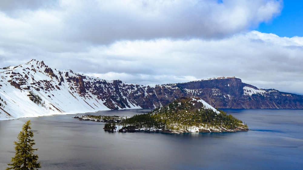 green trees on mountain near lake under white clouds during daytime