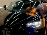 man in blue crew neck t-shirt standing beside black car