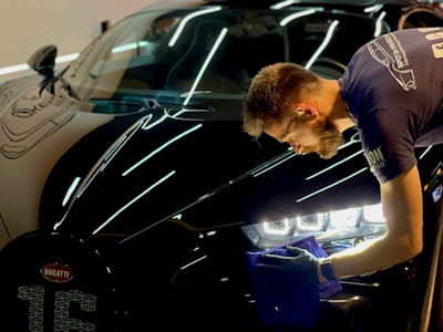 man in blue crew neck t-shirt standing beside black car