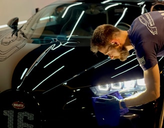 man in blue crew neck t-shirt standing beside black car