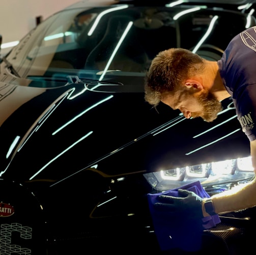 man in blue crew neck t-shirt standing beside black car