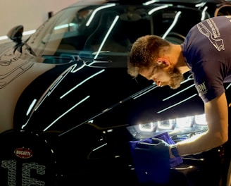 man in blue crew neck t-shirt standing beside black car