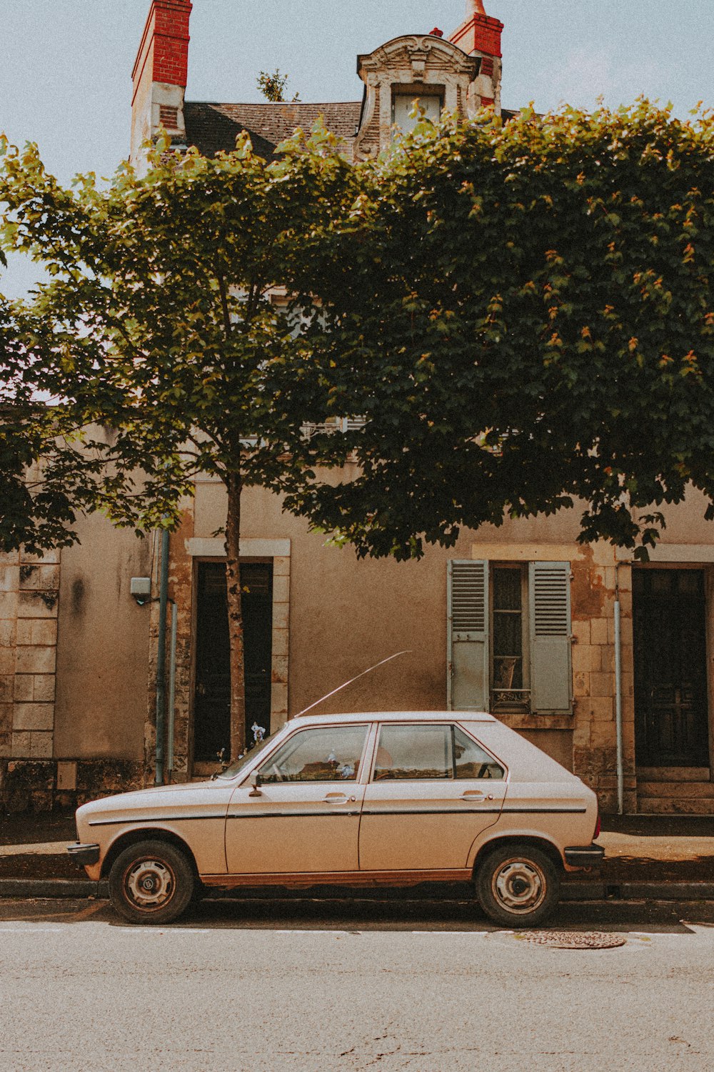 white sedan parked beside brown concrete building during daytime