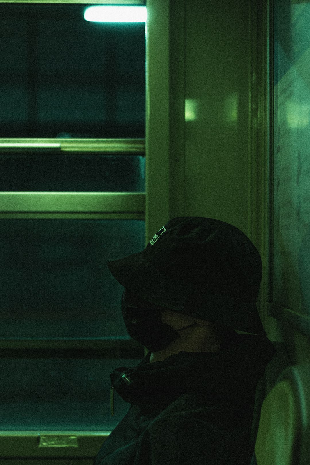 person in black hoodie sitting beside window