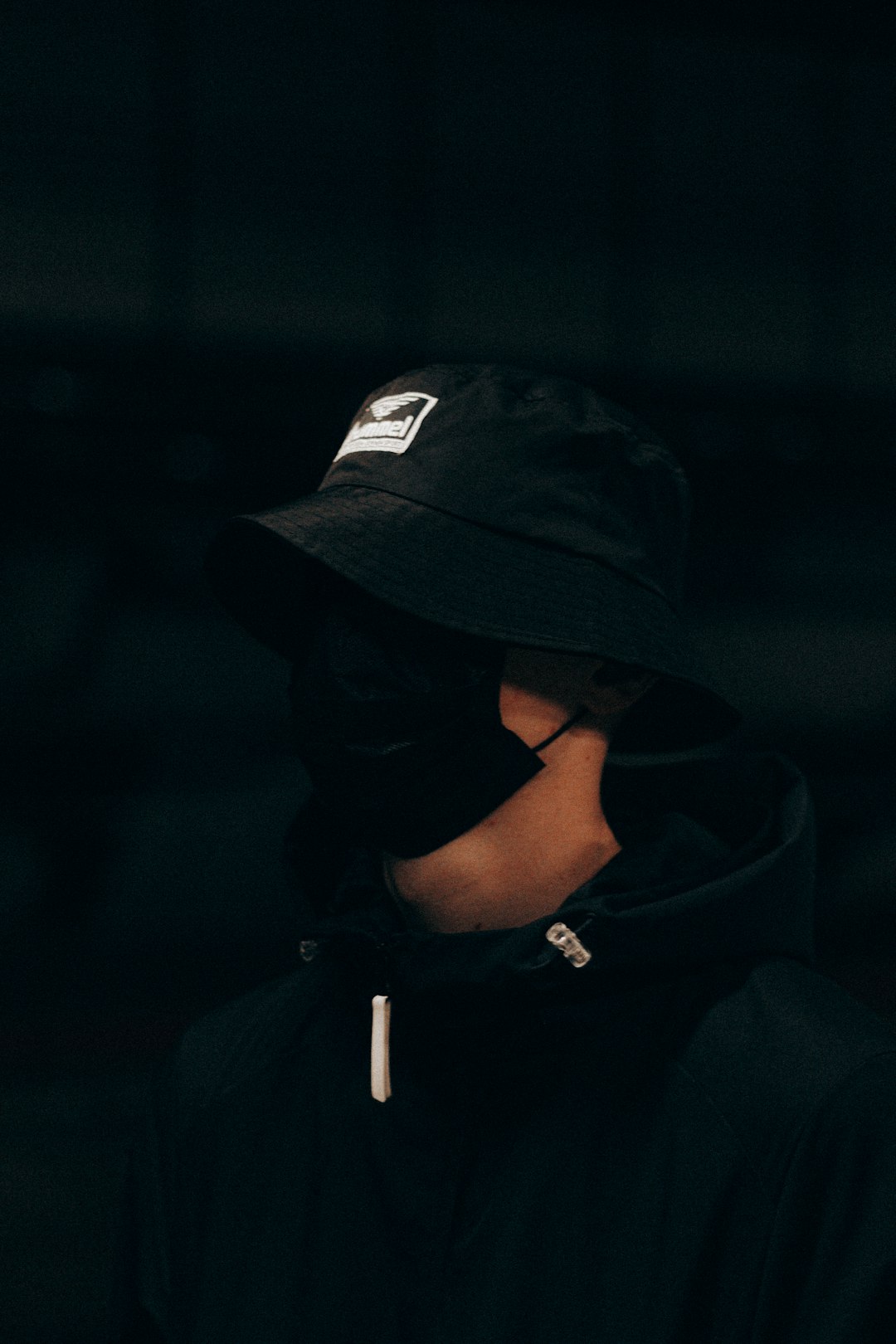man in black hoodie wearing black cap