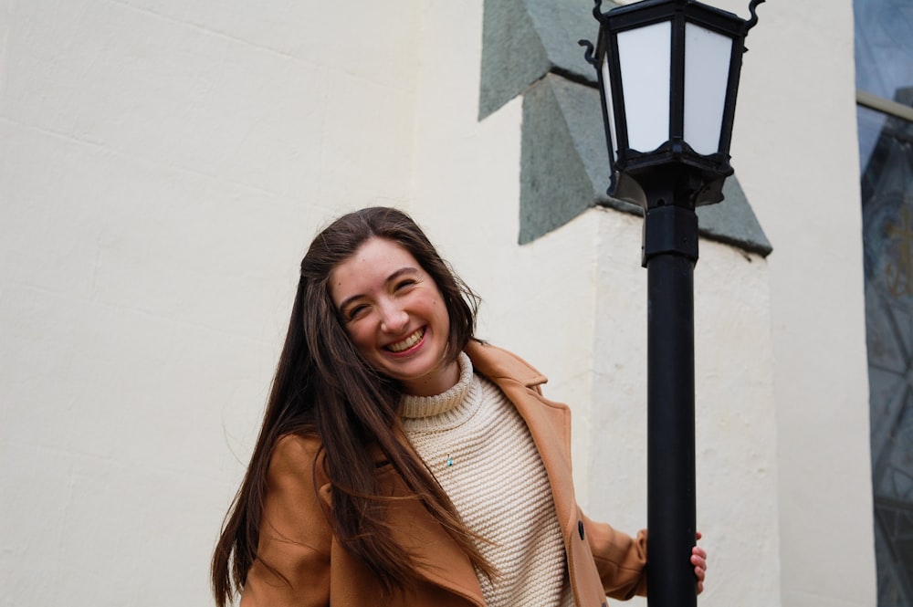 woman in brown scarf standing beside black lamp post