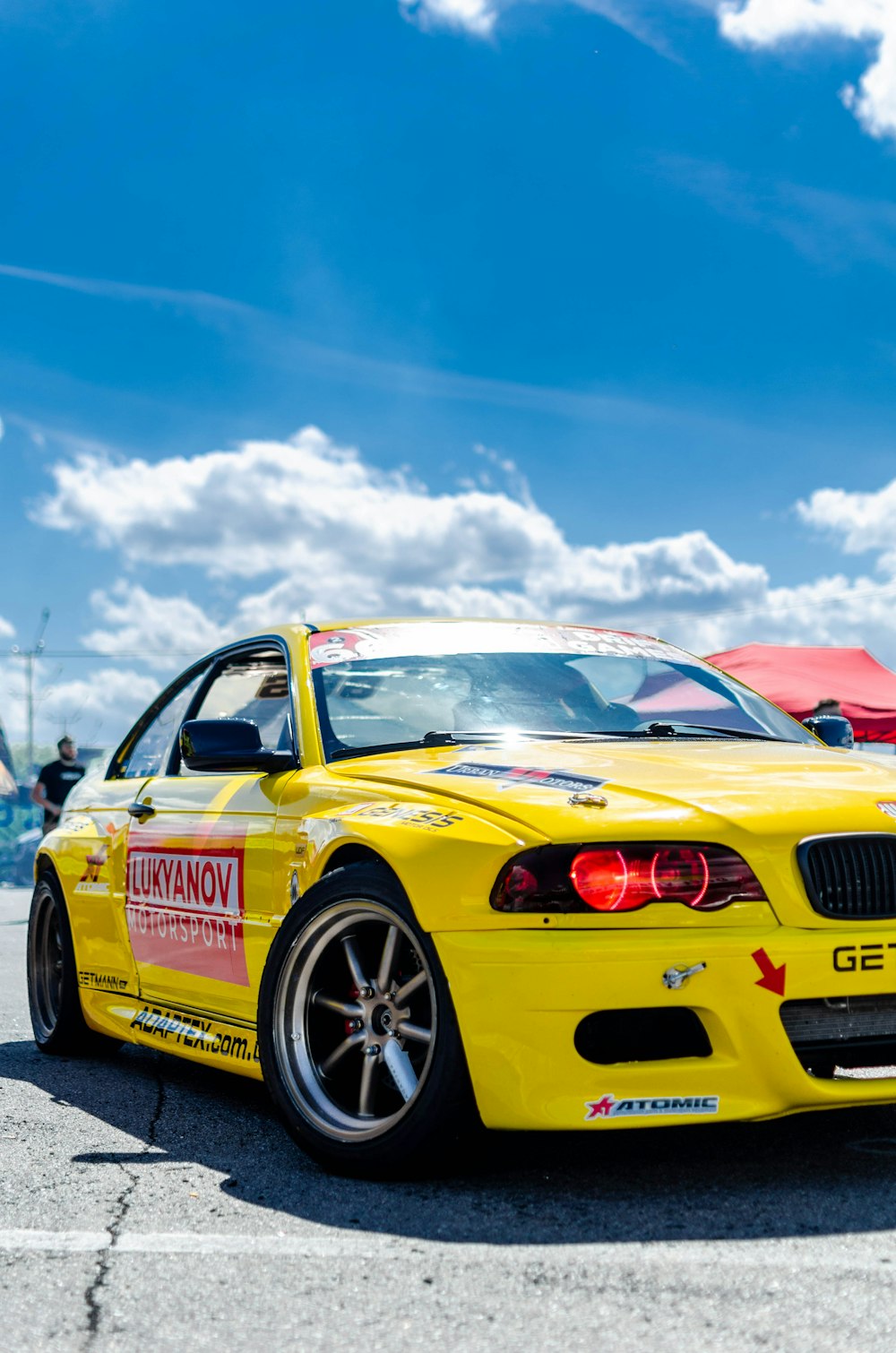 red and yellow porsche 911 on road under blue sky and white clouds during daytime