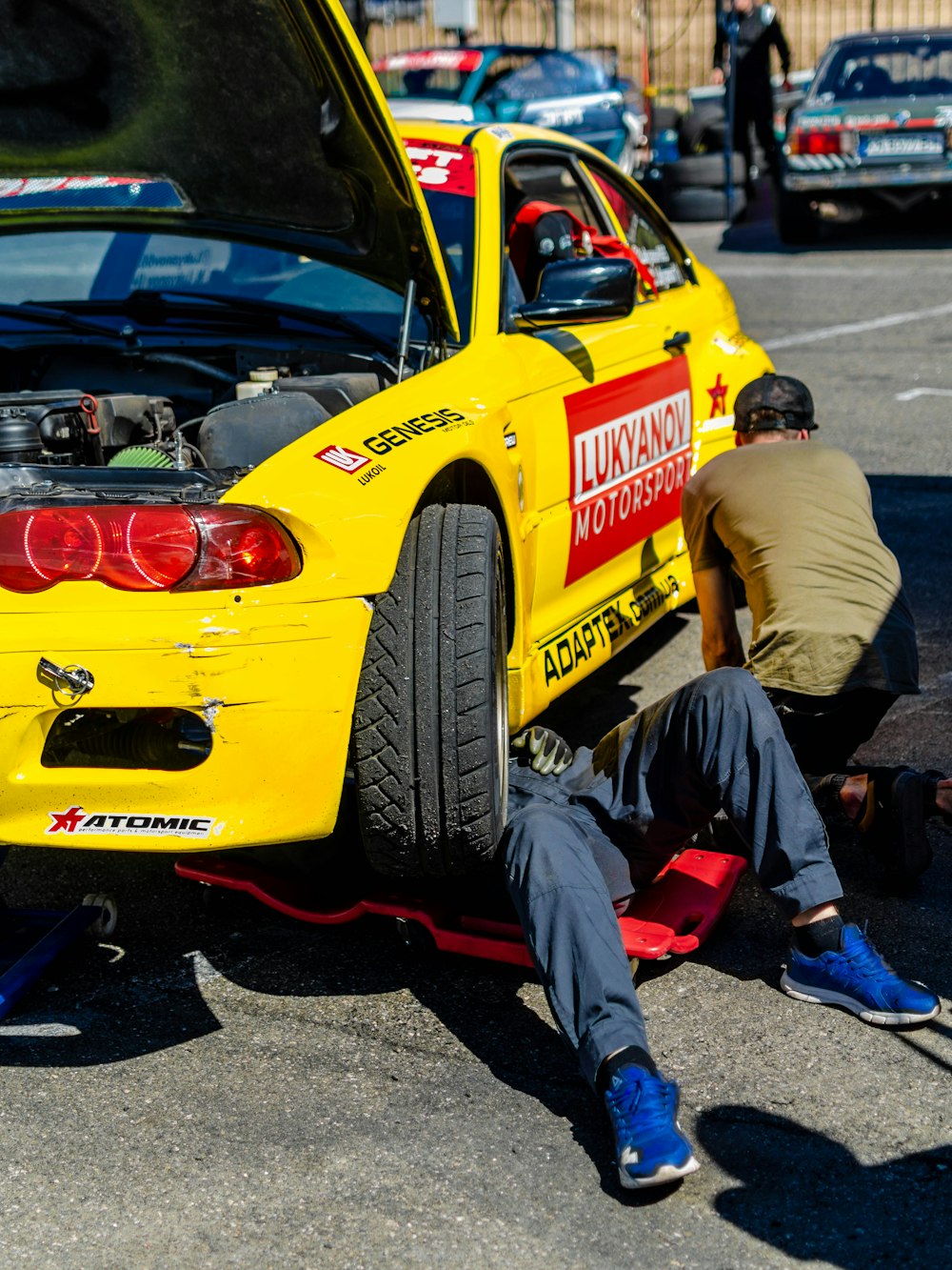 man in brown long sleeve shirt and blue denim jeans sitting on yellow and black car