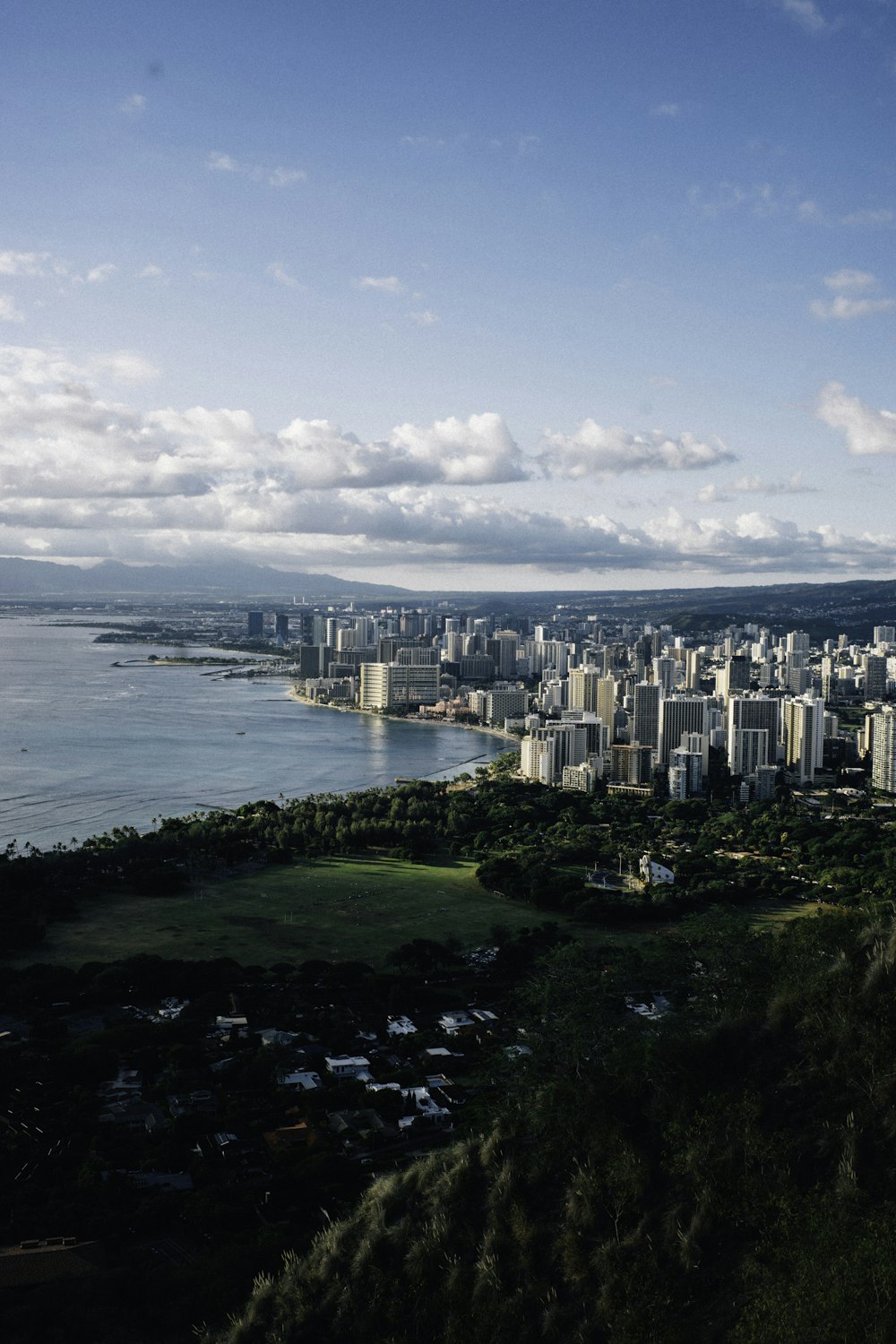 city skyline near body of water under blue and white sunny cloudy sky during daytime