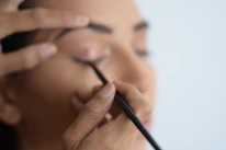 A close-up of a skilled artist applying permanent makeup on a client's eyebrow, highlighting precision and care.
