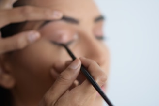 Close-up of a hand holding a sleek brow liner pencil with soft natural lighting.