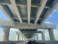 Engineers inspecting reinforced pavement layers on a busy highway under clear skies.