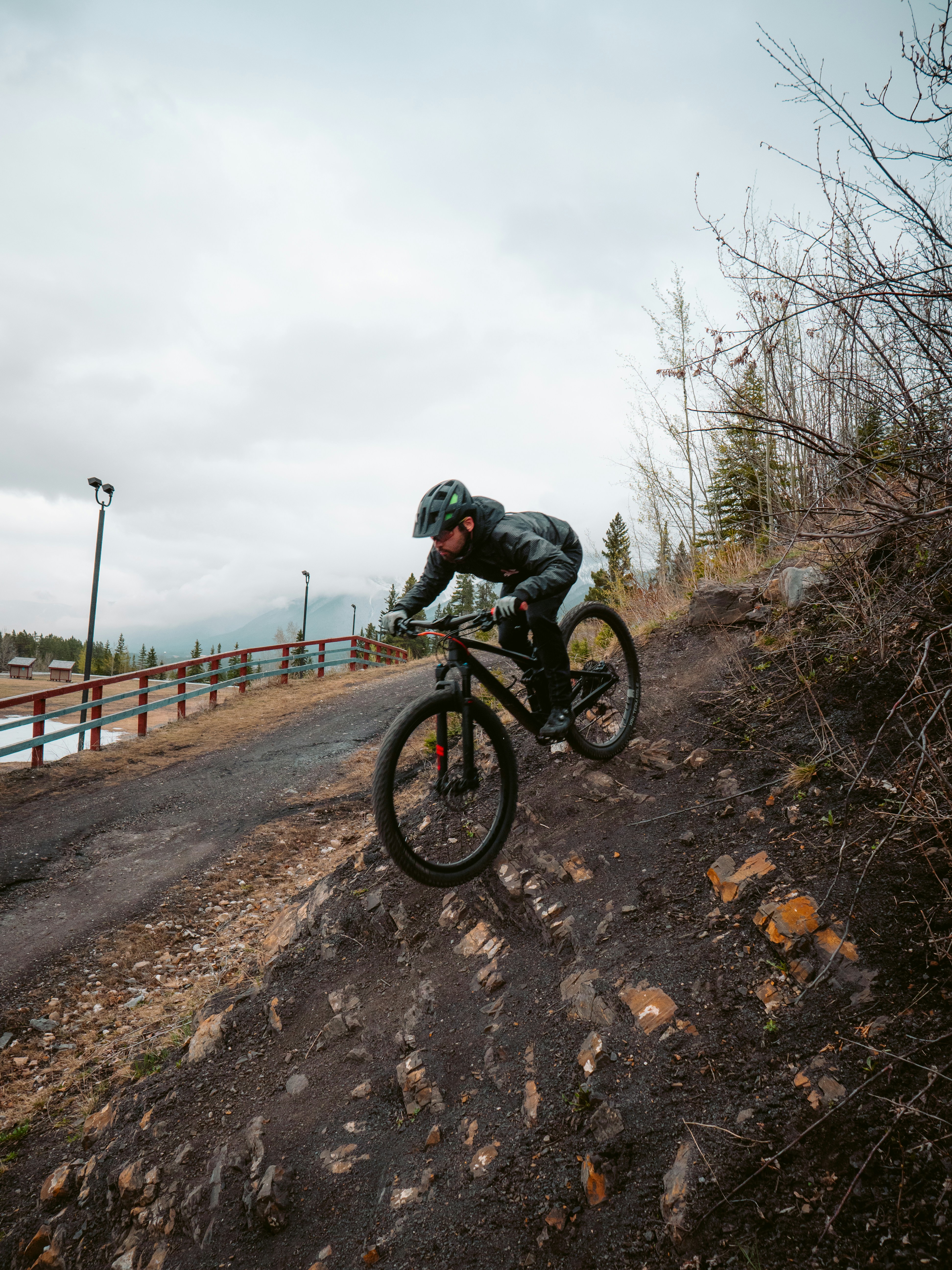 Hombre con chaqueta negra montando en bicicleta de montaña negra en camino de tierra marrón durante el día