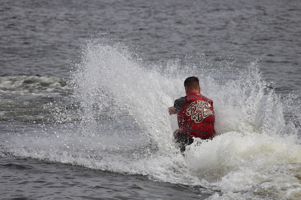 man in red shirt surfing on sea waves during daytime