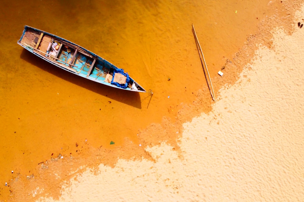 white and blue boat on brown sand