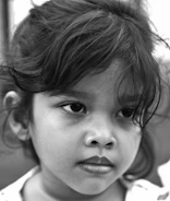 Black and white close-up of a child’s thoughtful expression in a studio setting.