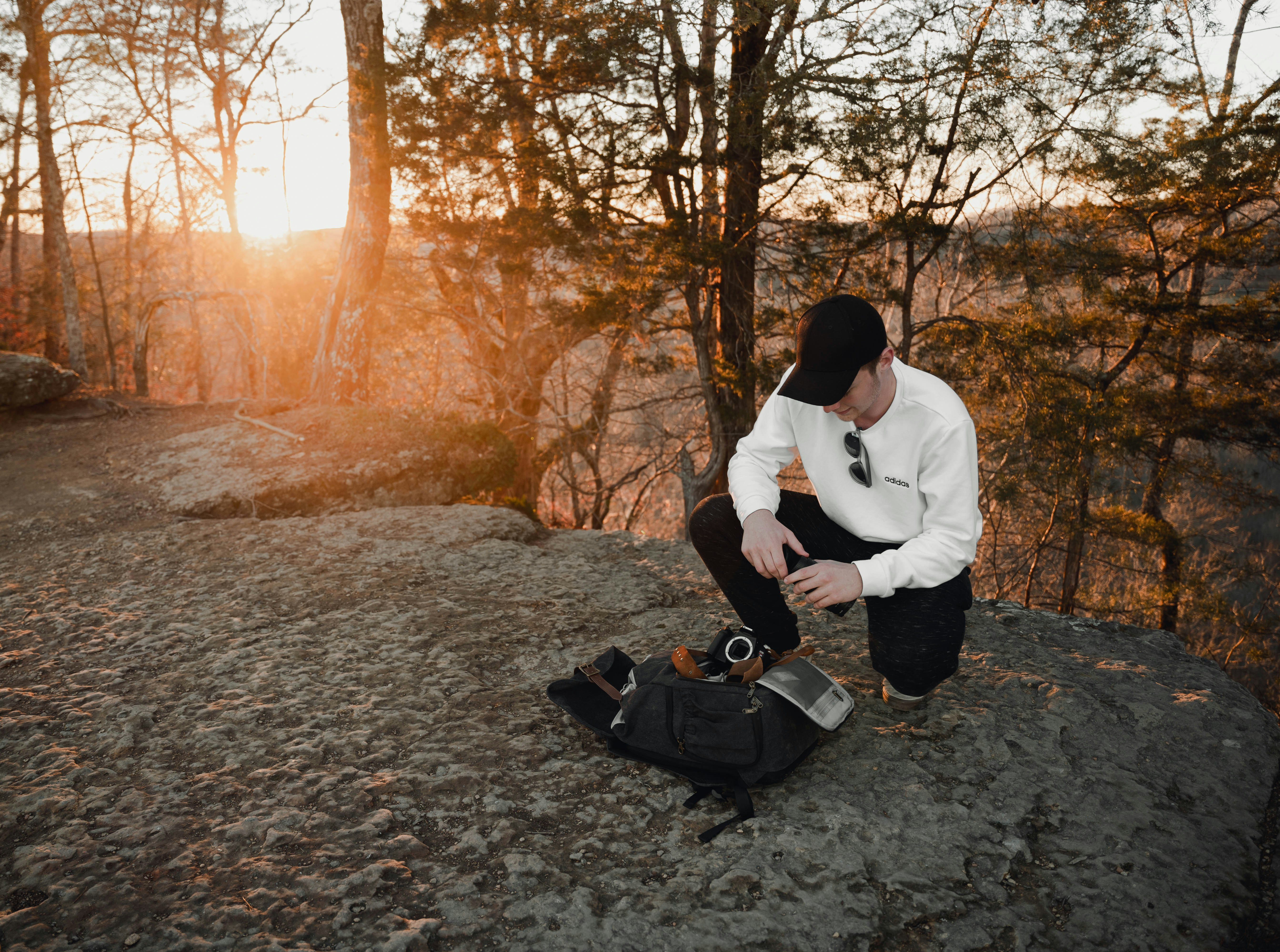 man in white dress shirt and black pants sitting on gray concrete floor