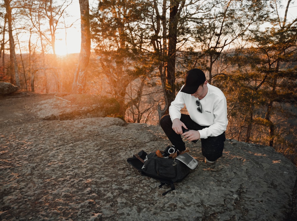 man in white dress shirt and black pants sitting on gray concrete floor