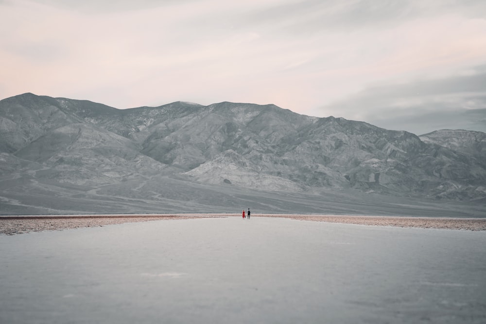 person walking on brown sand near body of water during daytime