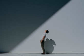 man in white t-shirt and white shorts standing on white wall