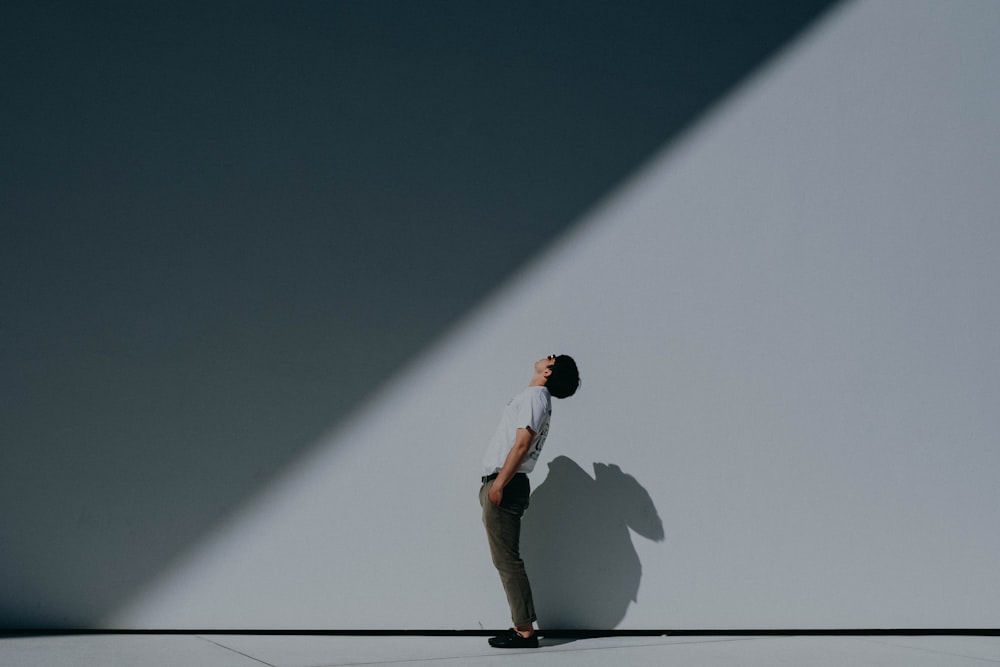 man in white t-shirt and white shorts standing on white wall