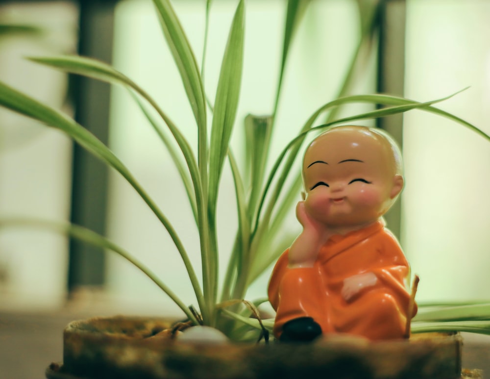 brown ceramic figurine beside green plant