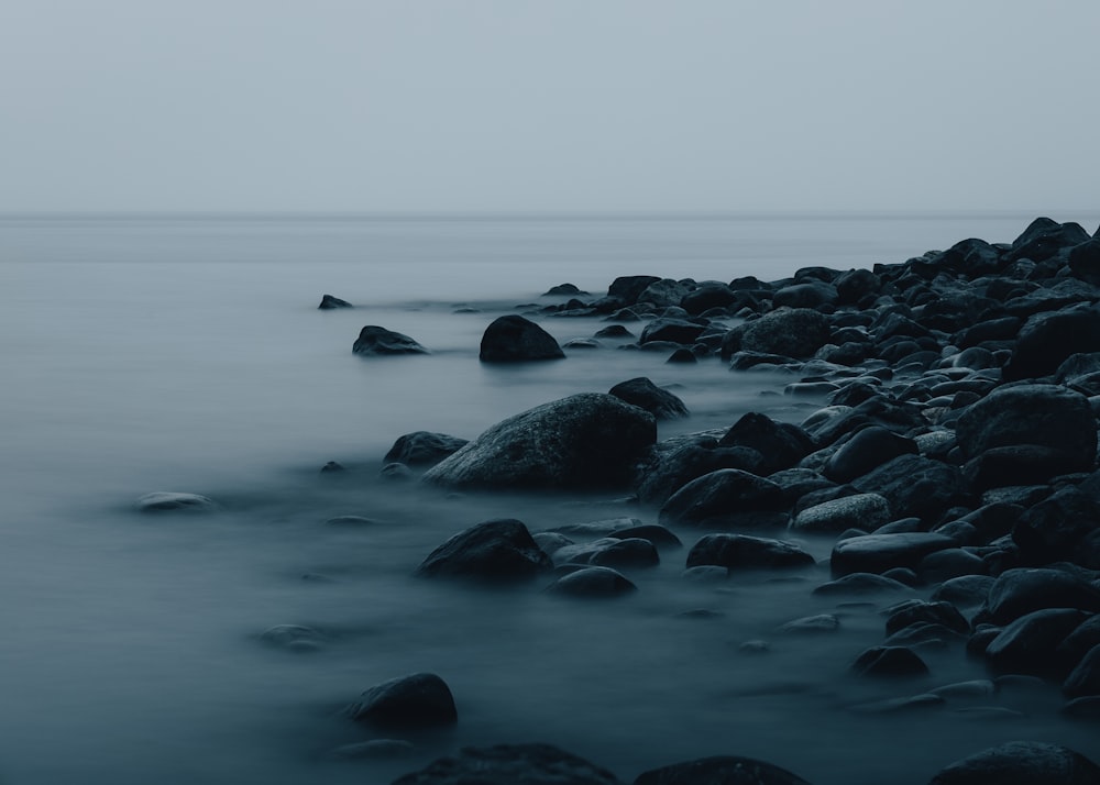 black rocks on body of water during daytime