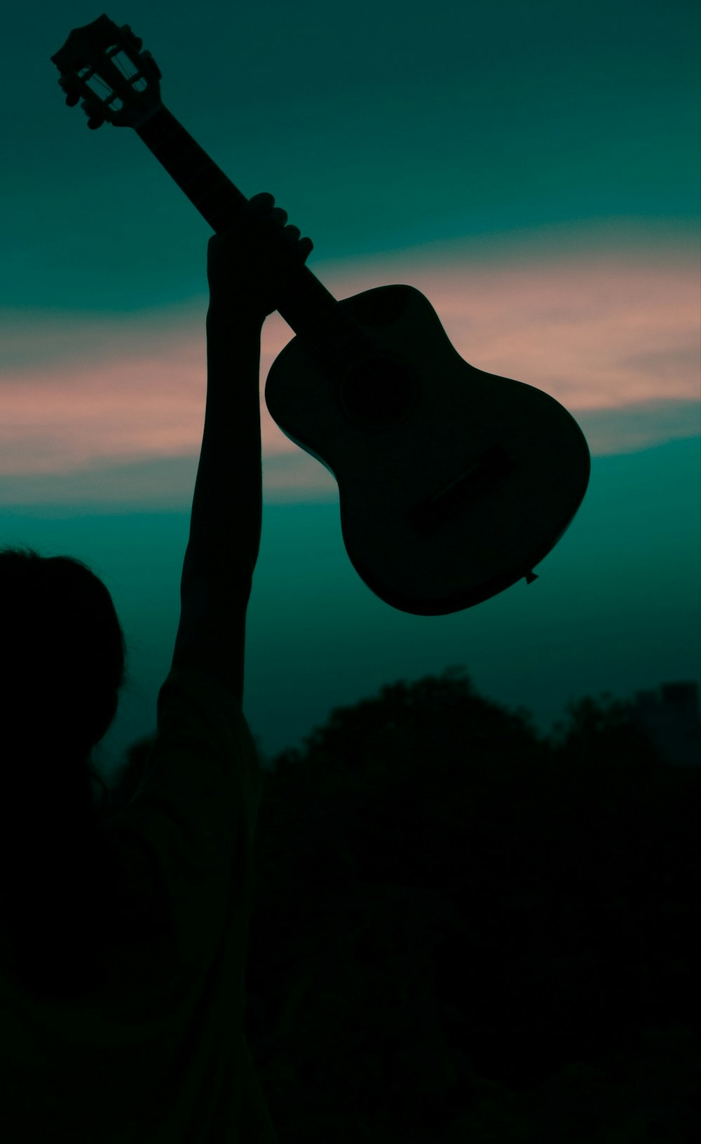 silhueta do homem segurando a guitarra durante o pôr do sol